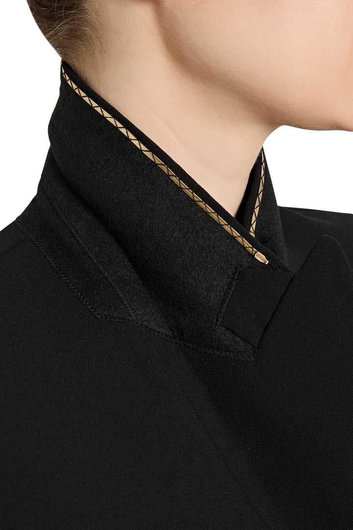 Close-up of a black garment with gold trim on a white background