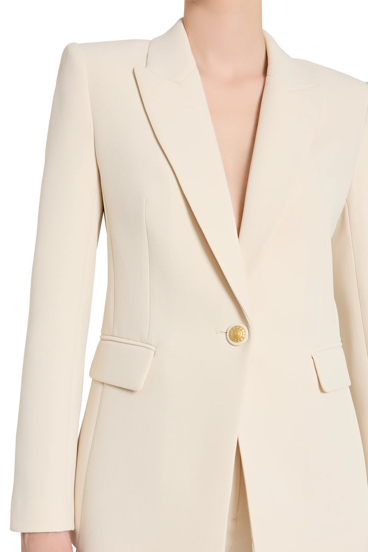 Beige blazer with a gold button on a white background