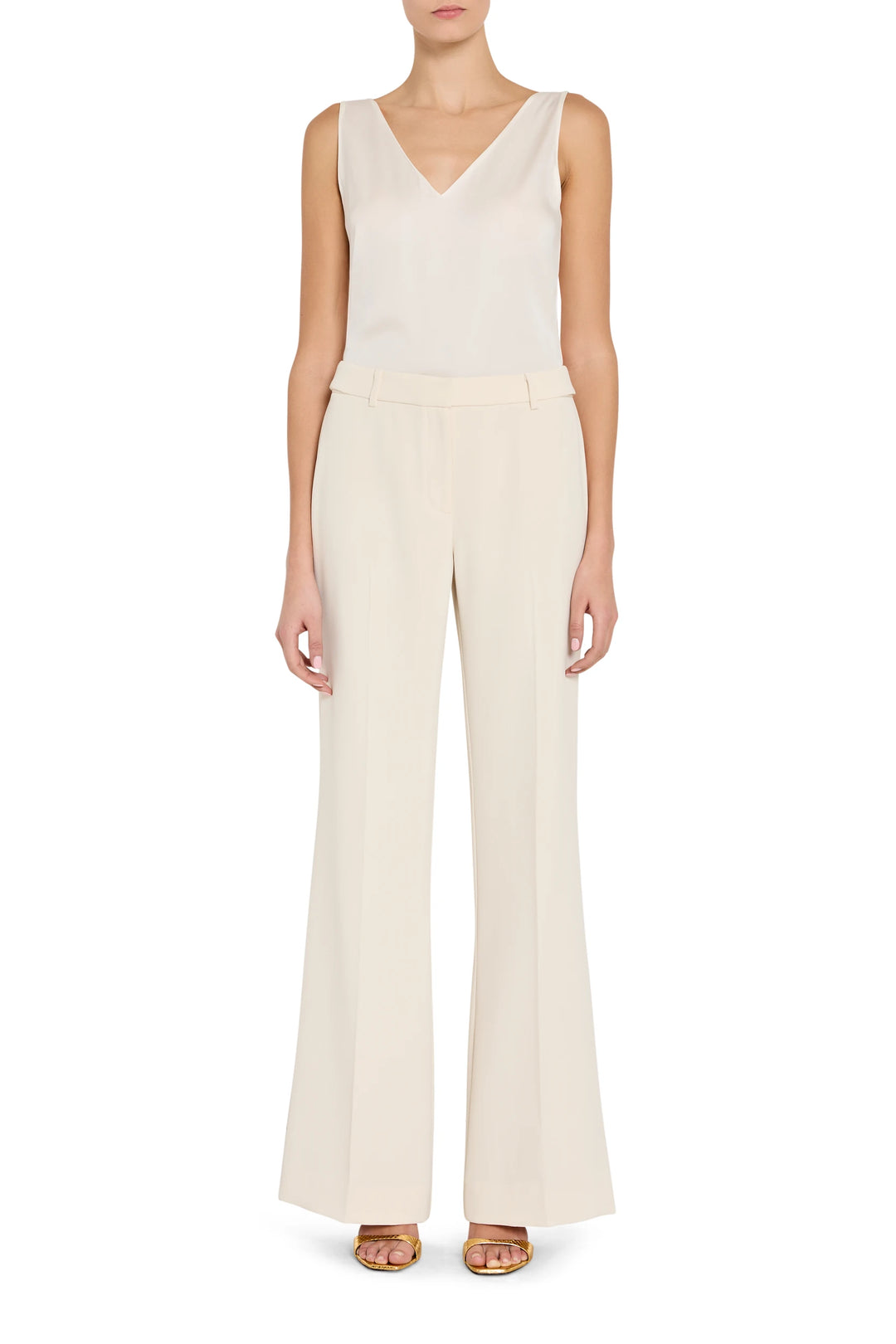 Woman wearing a white sleeveless top and wide-leg pants on a white background