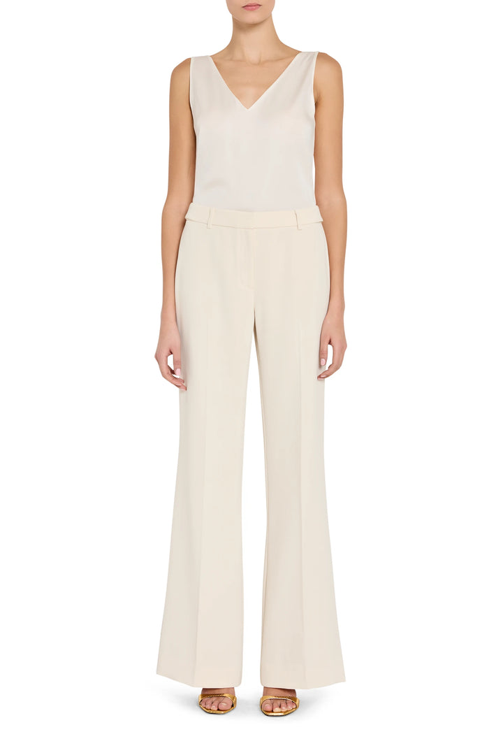 Woman wearing a white sleeveless top and wide-leg pants on a white background