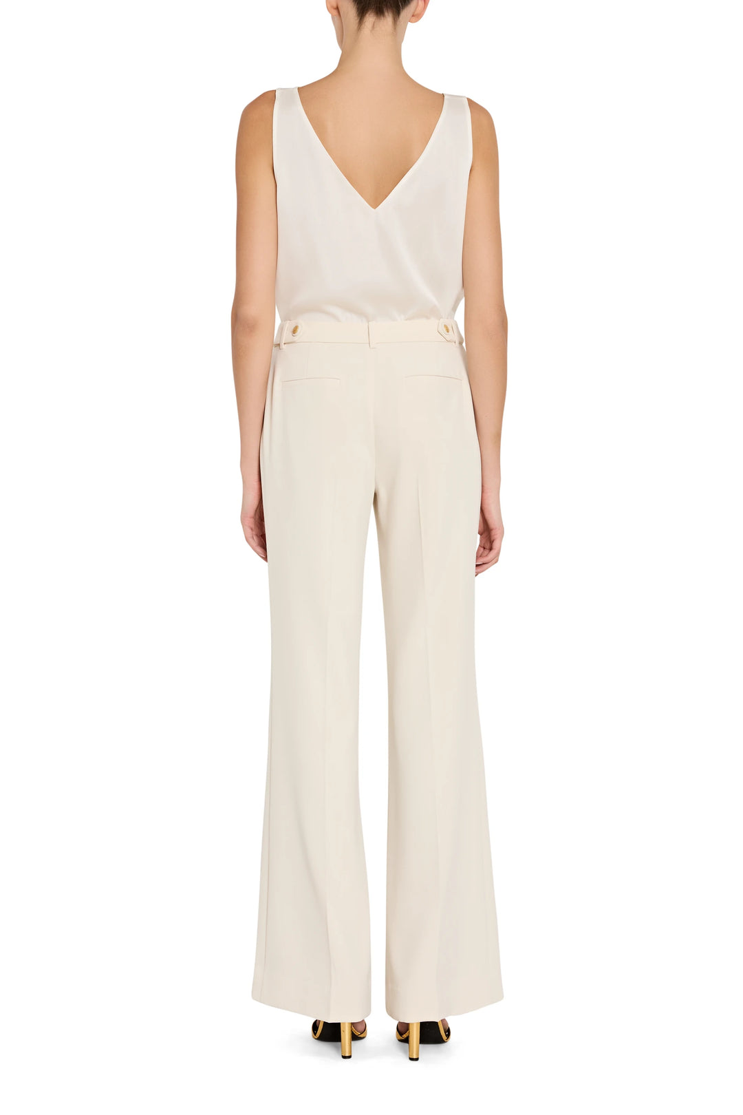 Woman wearing a white sleeveless top and pants on a white background