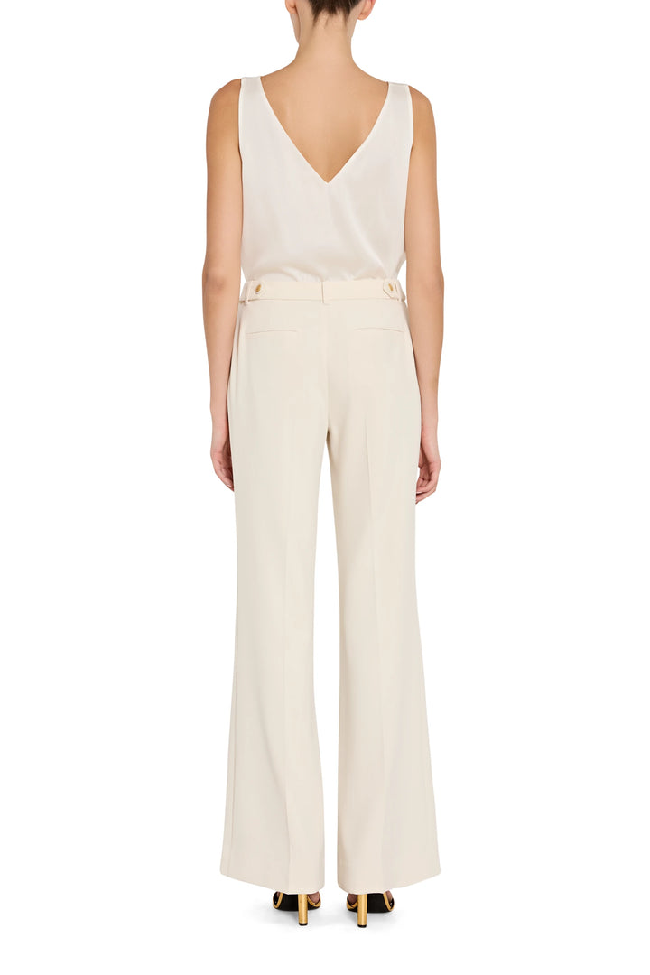 Woman wearing a white sleeveless top and pants on a white background