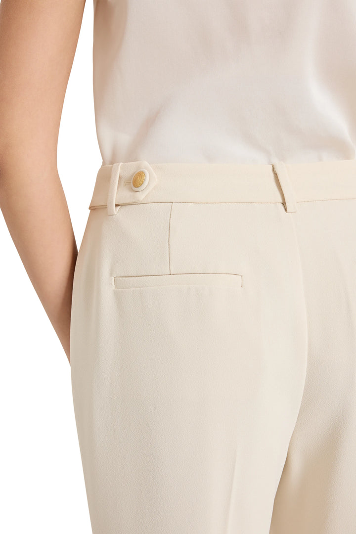Close-up of beige pants with a white shirt on a plain background