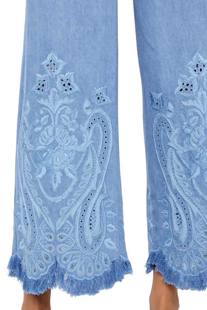 Detail of cropped jean with hand-embroidered motifs and scalloped, fringed hems. detail view.