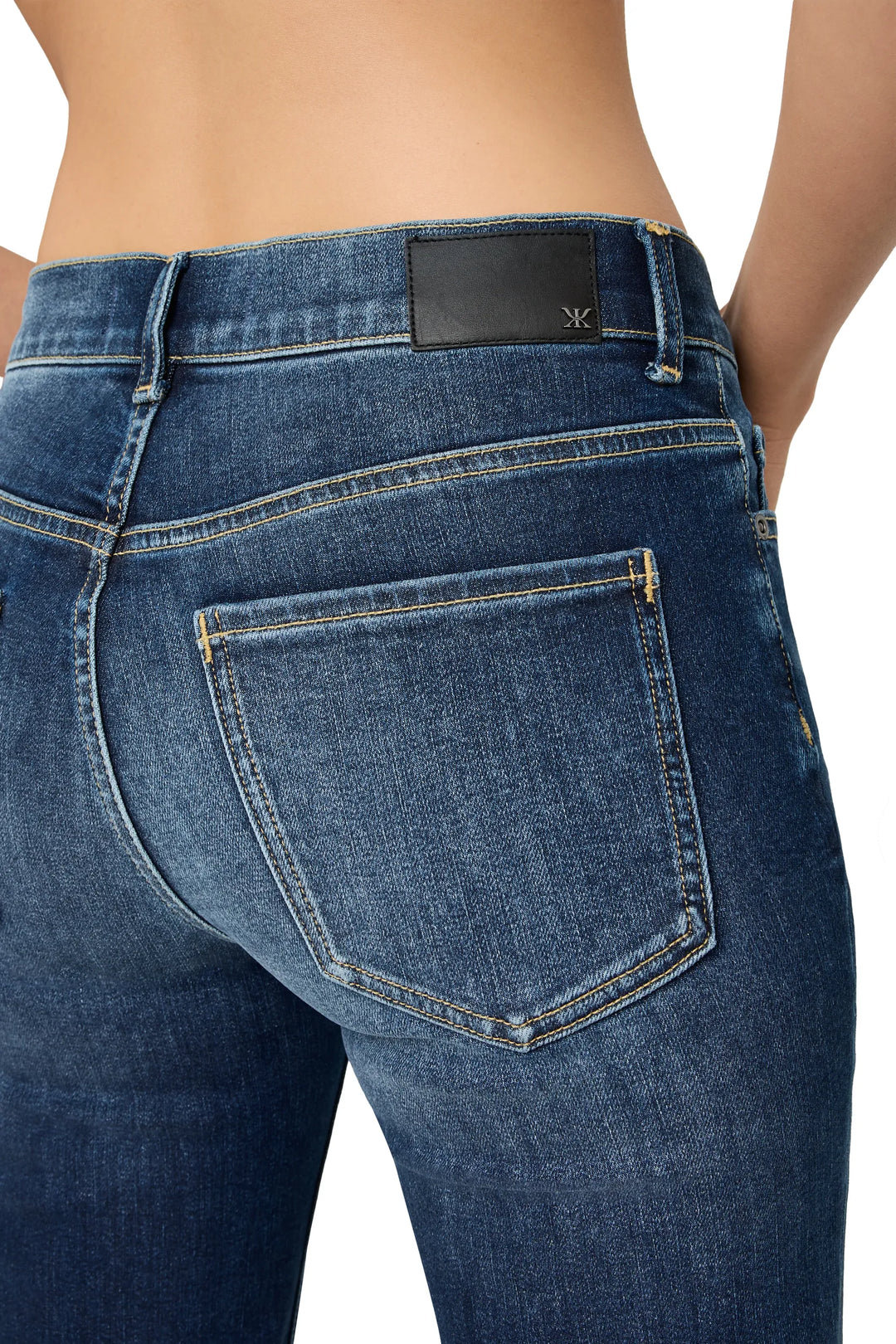 Low-rise, classic pocket denim with streamlined straight silhouette and subtle back yoke; back view on model.