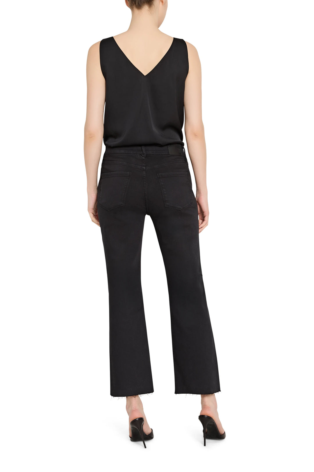 Person wearing a black sleeveless top and black pants on a white background