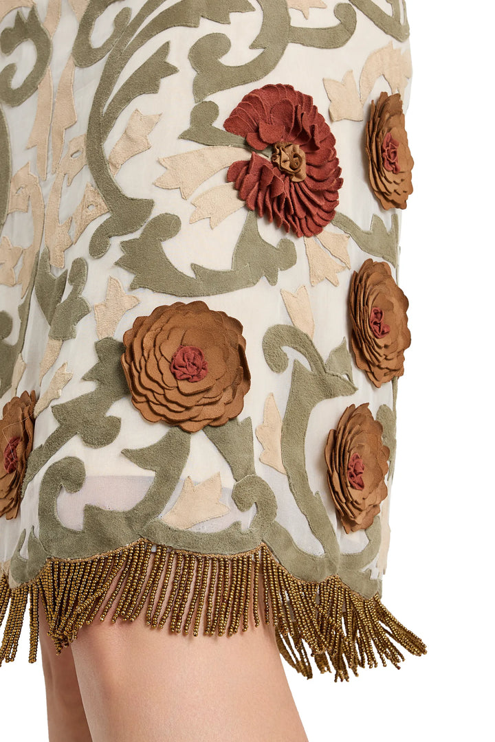 Detail of organza skirt with floral appliqué embroidery, beaded fringe hem, and leaf motif. Detail view.