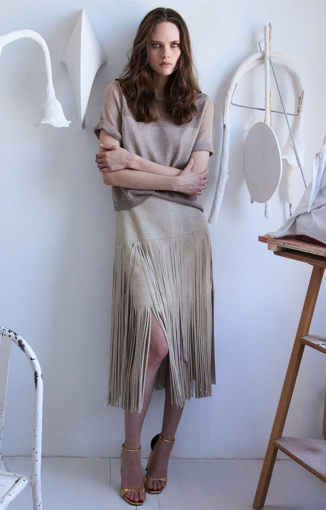 Fringe leather skirt with straight silhouette, mid-length cut, fringe trim hem; front view on model.