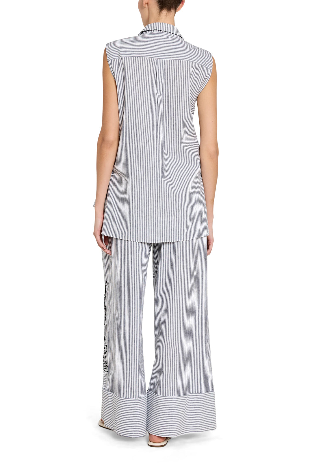 Woman wearing a sleeveless striped shirt and wide-leg pants on a white background