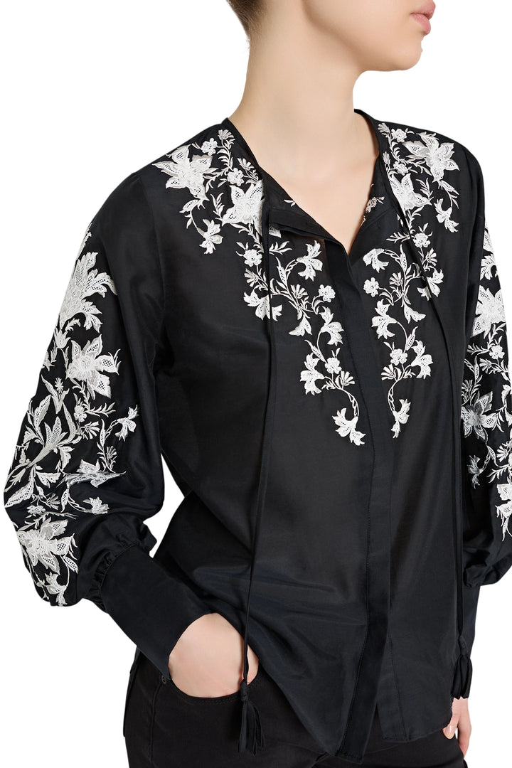 Black blouse with white floral embroidery on a plain background
