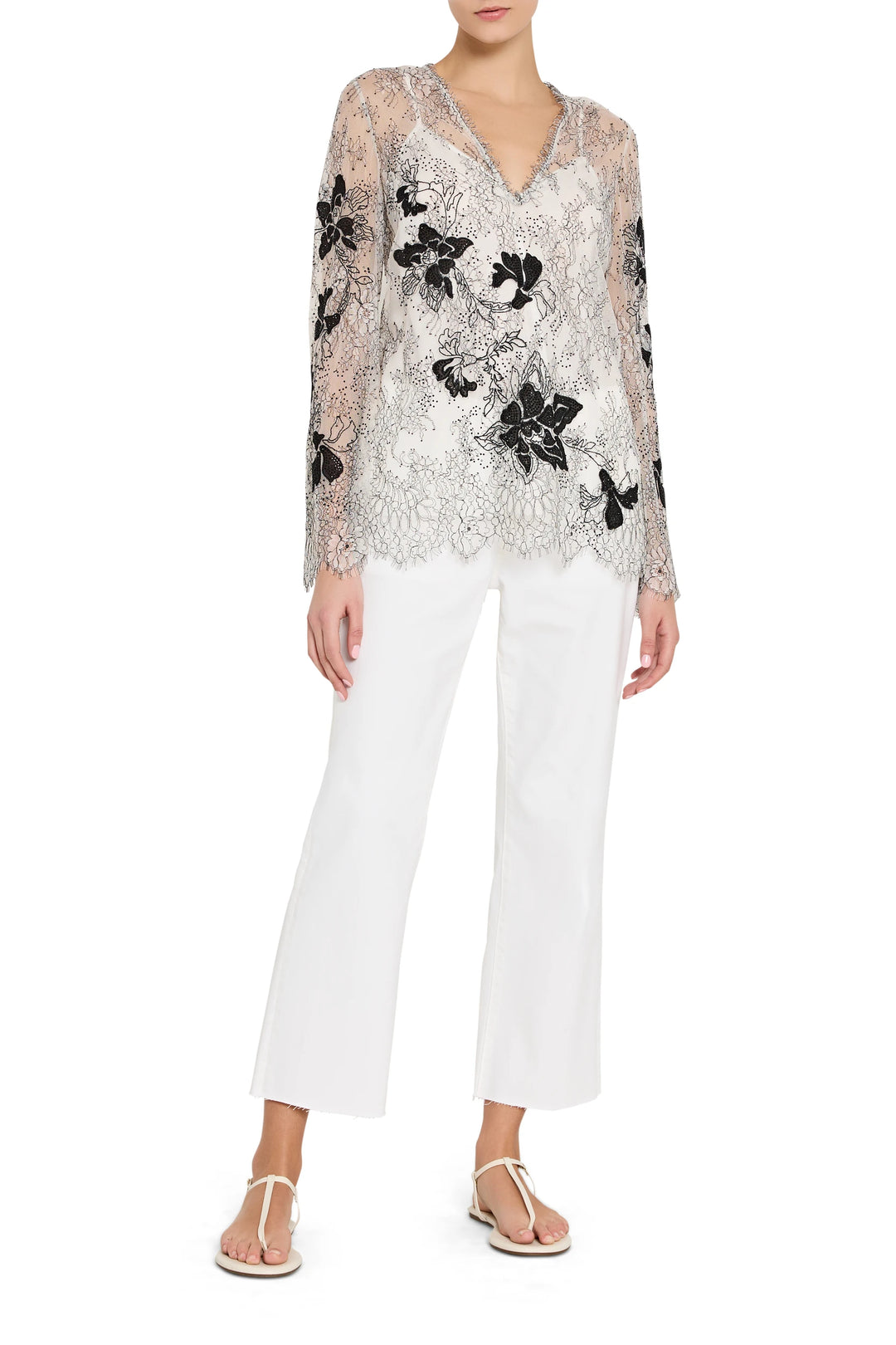 Woman wearing a floral sequin top and white pants on a white background