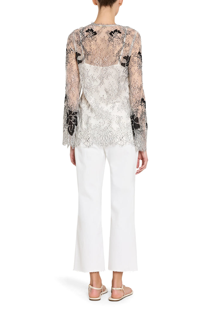 Woman wearing a floral lace top and white pants on a white background