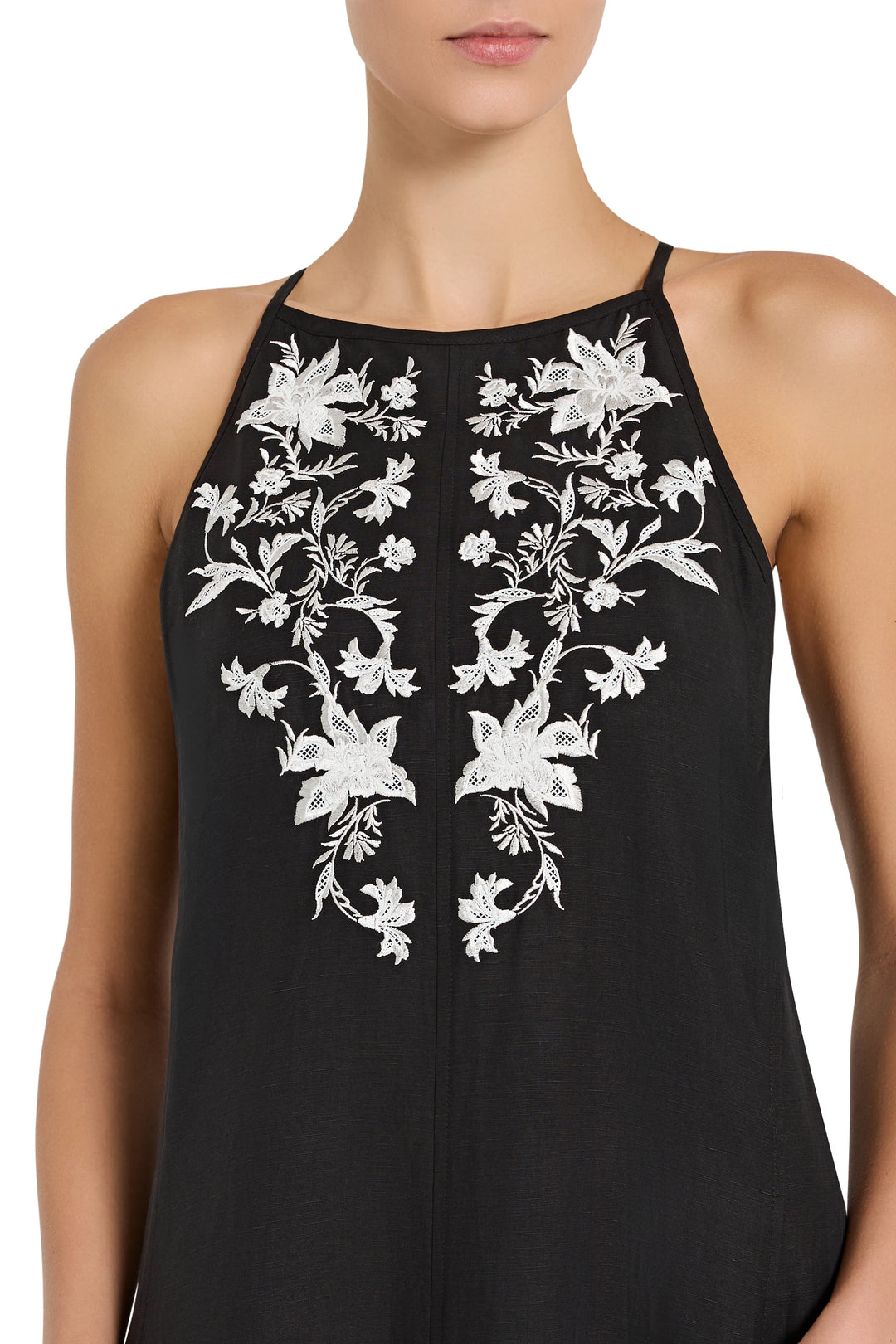 Black sleeveless top with white floral embroidery on a white background