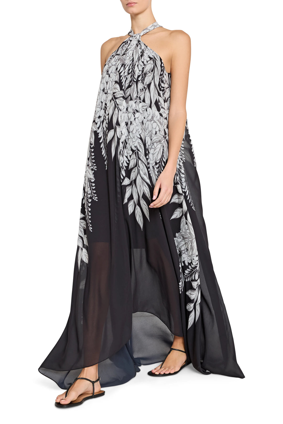 Woman wearing a black and white floral halter neck dress on a white background