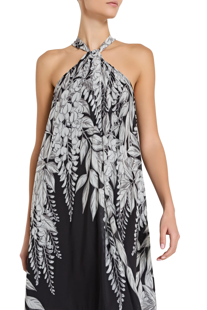 Woman wearing a black and white floral halter dress on a white background