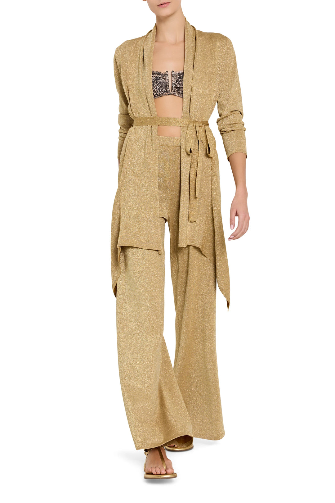 Woman wearing a beige outfit with a matching cardigan and pants on a white background
