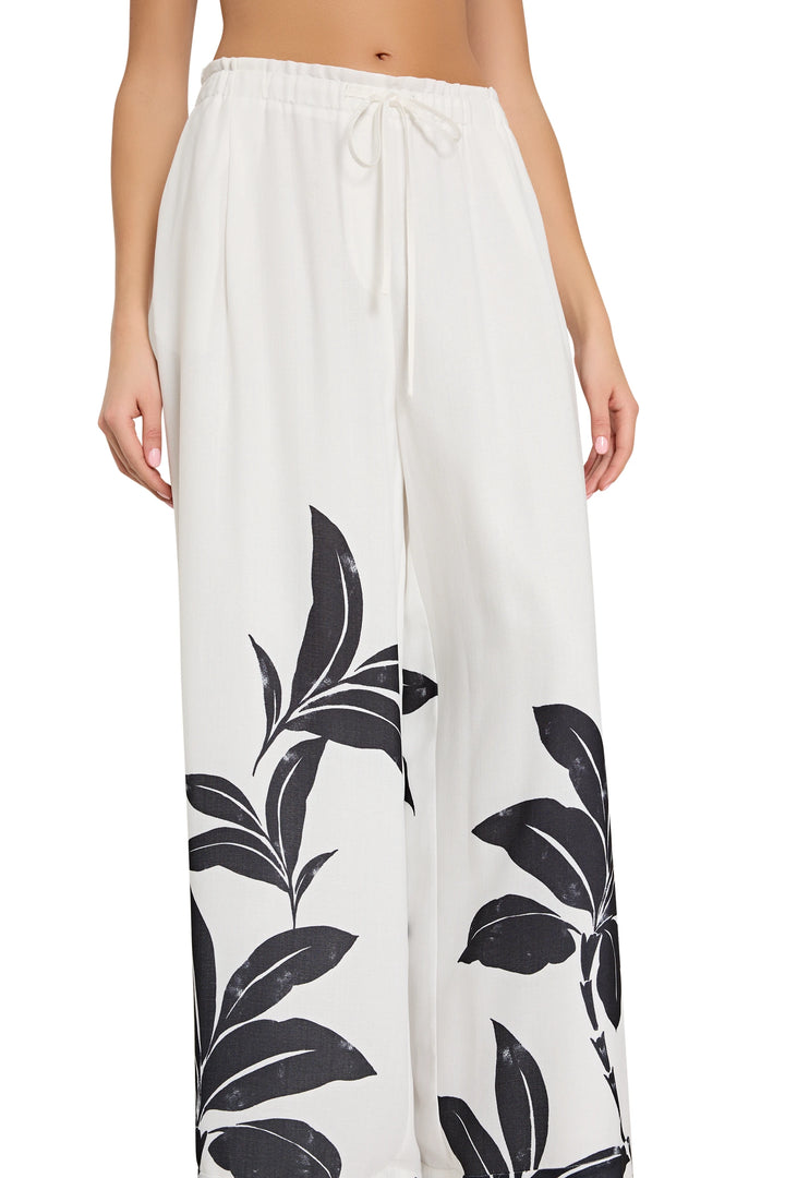 White pants with black leaf pattern worn by a person on a white background