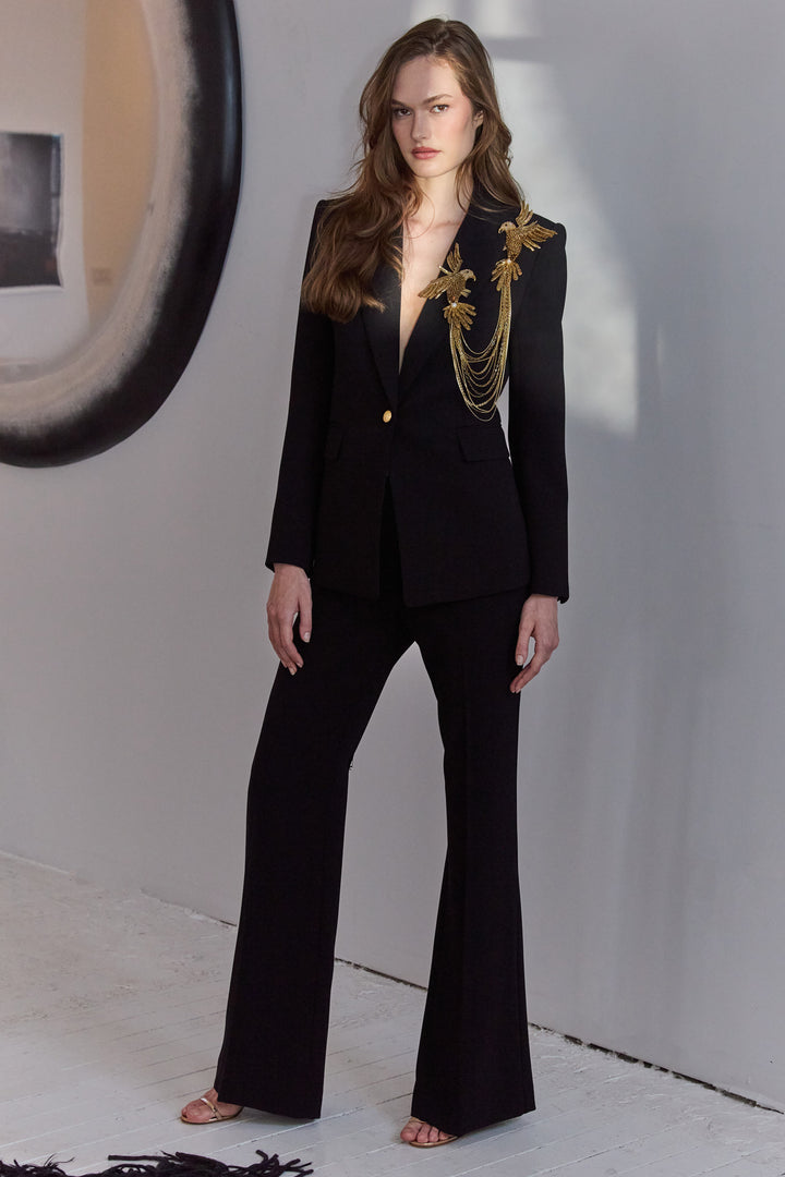 Woman wearing a black suit with gold accents in a minimalistic setting