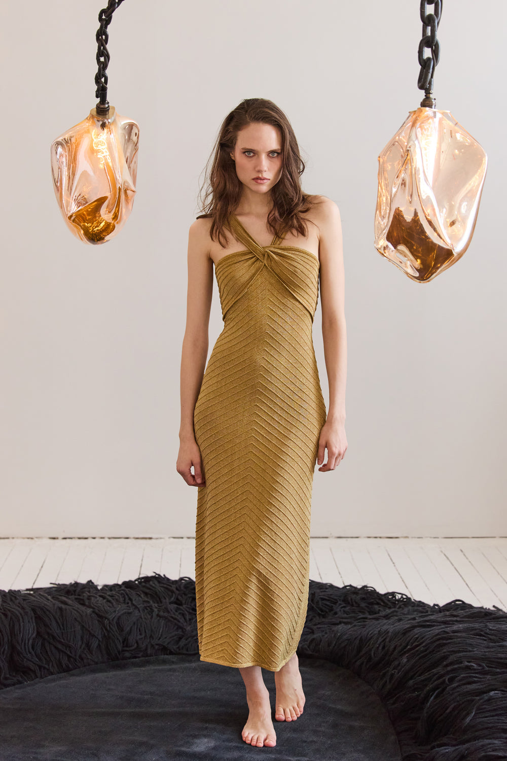 Woman wearing a mustard yellow dress standing in a room with modern decor.