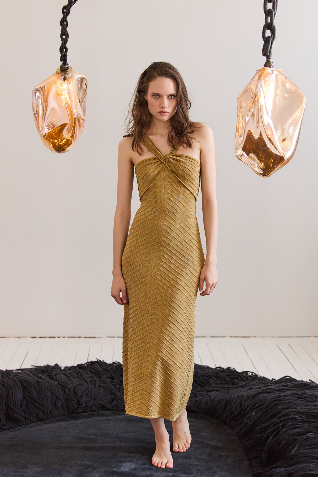 Woman wearing a mustard yellow dress standing in a room with modern decor.